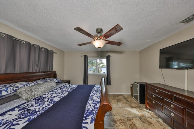 bedroom with ceiling fan and a textured ceiling