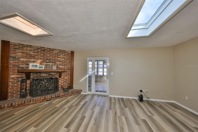 unfurnished living room featuring light hardwood / wood-style floors, a brick fireplace, and a textured ceiling