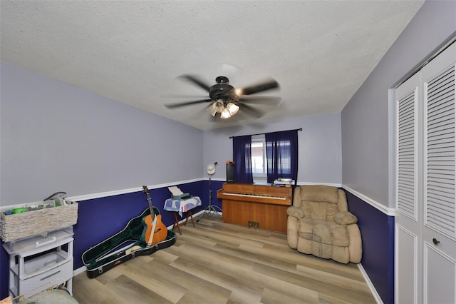 bedroom featuring ceiling fan, light hardwood / wood-style floors, a closet, and a textured ceiling