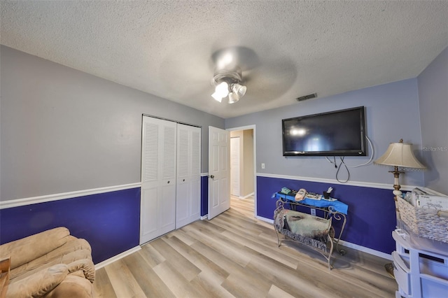 interior space featuring ceiling fan, light hardwood / wood-style flooring, and a textured ceiling