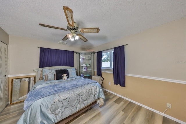 bedroom featuring ceiling fan, hardwood / wood-style floors, and a textured ceiling