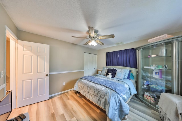 bedroom with a closet, ceiling fan, hardwood / wood-style floors, and a textured ceiling