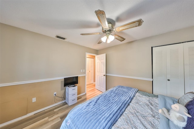 bedroom with ceiling fan, a textured ceiling, light wood-type flooring, and a closet