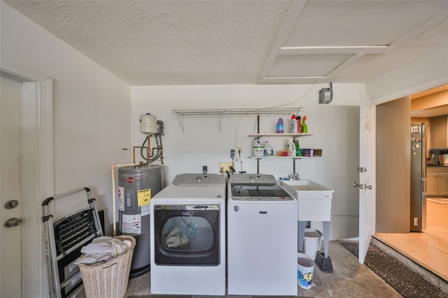 washroom featuring washing machine and dryer, water heater, and a textured ceiling