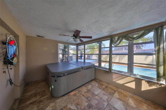 unfurnished sunroom with ceiling fan