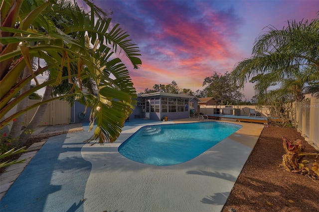 pool at dusk with a sunroom and a patio