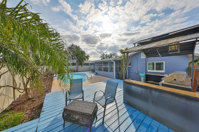 wooden deck featuring a fenced in pool, a sunroom, and a grill