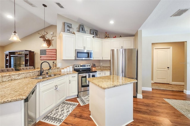 kitchen with appliances with stainless steel finishes, decorative light fixtures, white cabinetry, sink, and kitchen peninsula