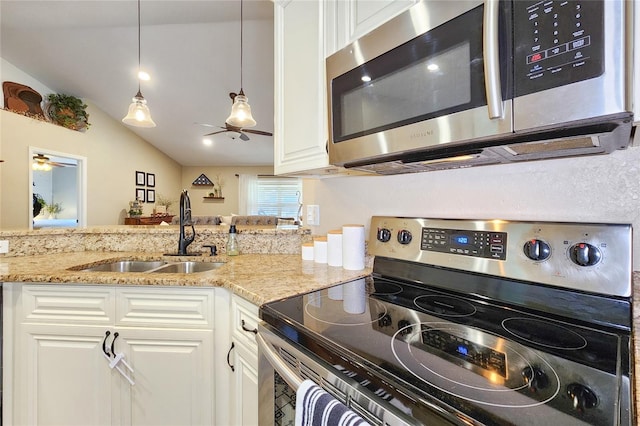 kitchen featuring sink, stainless steel appliances, light stone counters, white cabinets, and decorative light fixtures