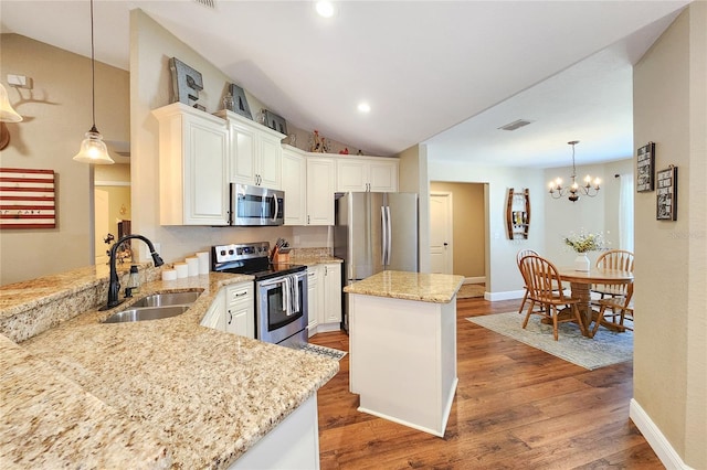 kitchen featuring lofted ceiling, sink, decorative light fixtures, appliances with stainless steel finishes, and kitchen peninsula