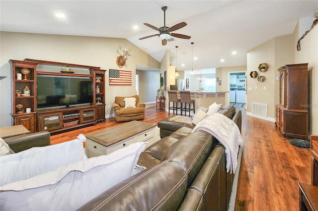 living room with hardwood / wood-style flooring, ceiling fan, and lofted ceiling