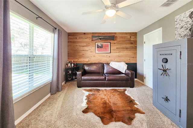 living room featuring carpet flooring, ceiling fan, and wood walls