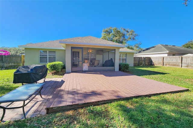 rear view of property with a wooden deck, a sunroom, and a lawn