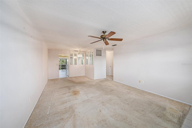 empty room featuring ceiling fan, light colored carpet, and a textured ceiling