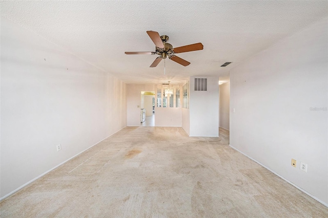 spare room featuring ceiling fan, light carpet, and a textured ceiling