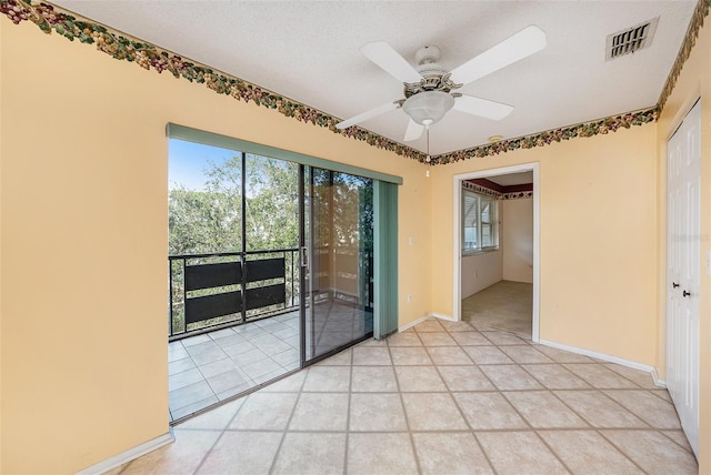 empty room featuring a textured ceiling, ceiling fan, and light tile patterned flooring