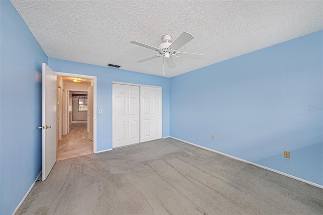 unfurnished bedroom featuring ceiling fan, light colored carpet, a closet, and a textured ceiling