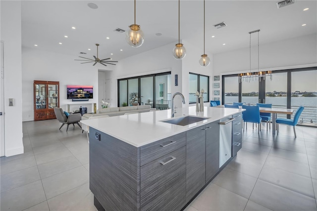 kitchen with a towering ceiling, pendant lighting, an island with sink, sink, and french doors