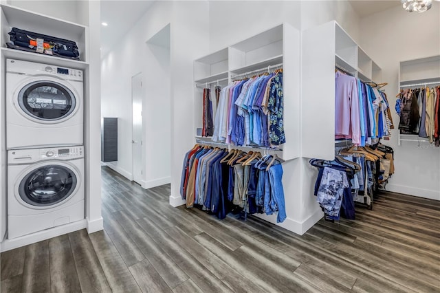 clothes washing area featuring hardwood / wood-style flooring, a towering ceiling, and stacked washing maching and dryer