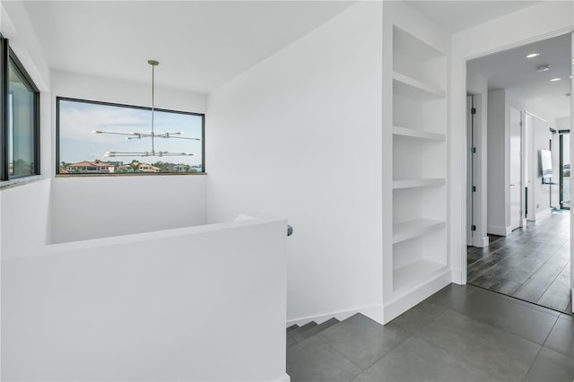 corridor with built in features and an inviting chandelier