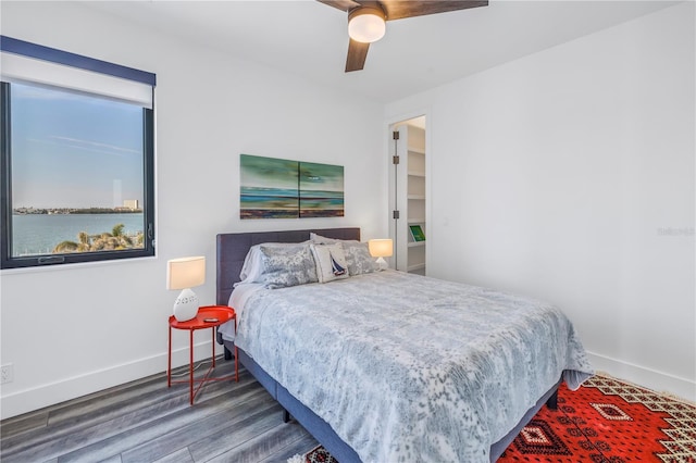 bedroom featuring wood-type flooring, ceiling fan, and a water view