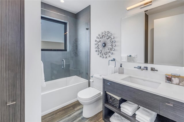 full bathroom featuring vanity, hardwood / wood-style floors, bath / shower combo with glass door, and toilet