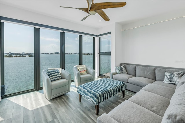 living room featuring wood-type flooring, a water view, and ceiling fan