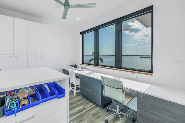 office area with hardwood / wood-style floors, a water view, built in desk, and ceiling fan