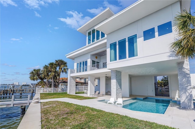 rear view of house with a balcony, a water view, a yard, and a patio area