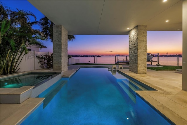 pool at dusk featuring a patio and a water view