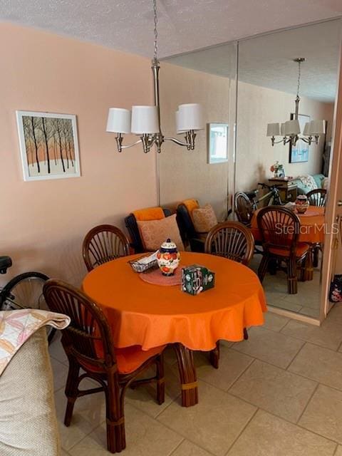 dining area with tile patterned flooring, a notable chandelier, and a textured ceiling