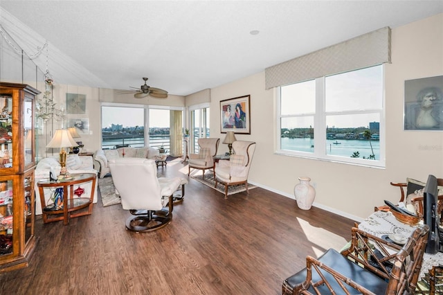 living room with a water view, dark hardwood / wood-style floors, and ceiling fan