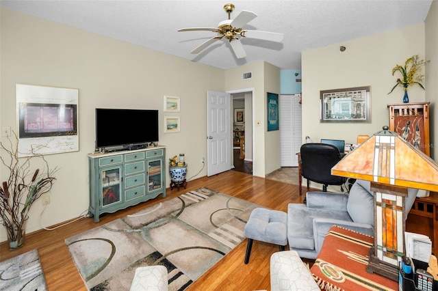 living room featuring hardwood / wood-style flooring, a textured ceiling, and ceiling fan