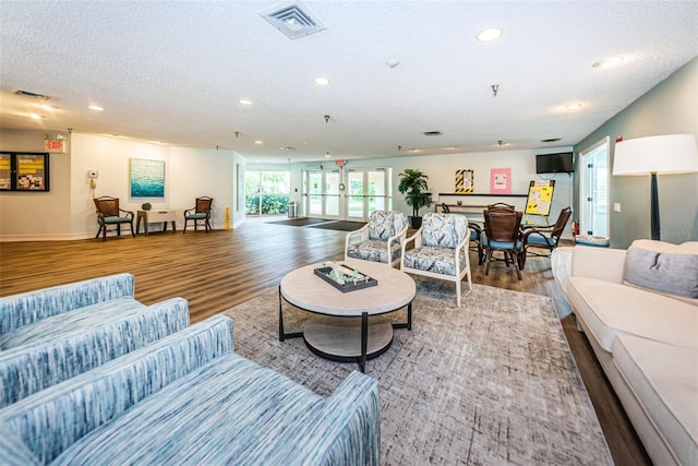 living room with wood-type flooring, french doors, and a textured ceiling