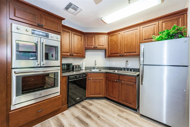 kitchen with light hardwood / wood-style flooring, sink, dark stone countertops, and black appliances