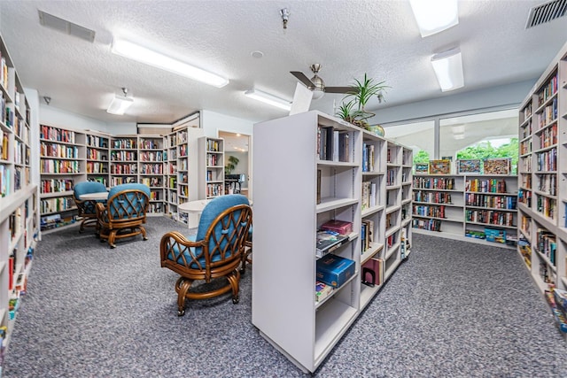 misc room with a textured ceiling and dark colored carpet