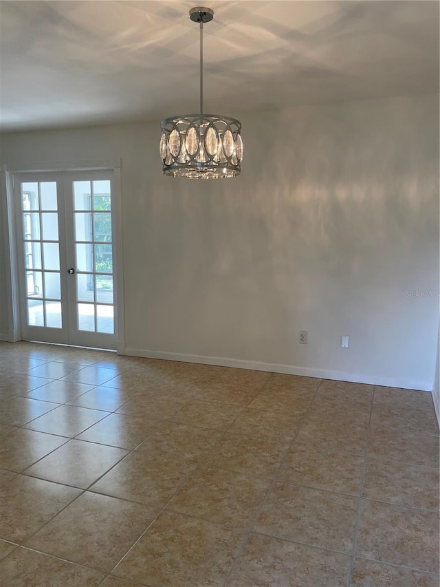 tiled spare room featuring french doors and a notable chandelier