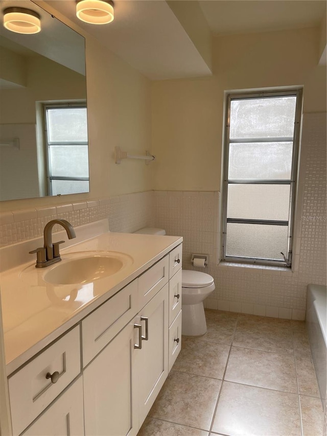 bathroom featuring vanity, a wealth of natural light, tile patterned floors, and toilet