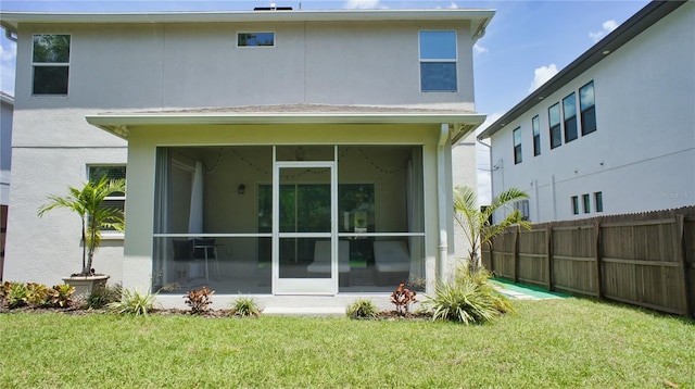 back of property featuring a sunroom and a lawn