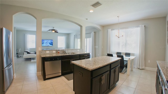 kitchen with pendant lighting, sink, a center island, light tile patterned floors, and stainless steel appliances