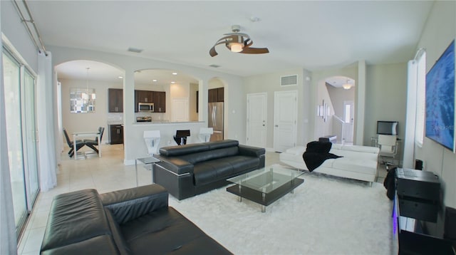 living room featuring ceiling fan with notable chandelier and light tile patterned flooring