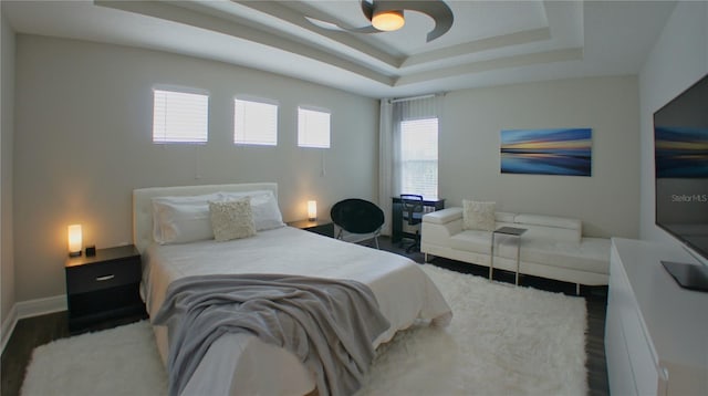 bedroom with ceiling fan, a tray ceiling, and hardwood / wood-style floors