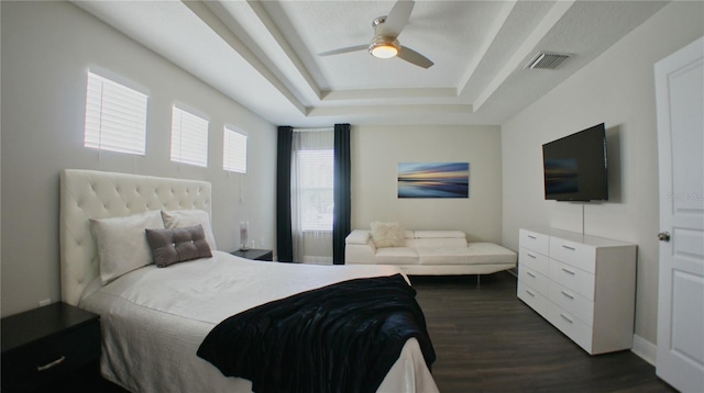 bedroom with a tray ceiling, dark hardwood / wood-style floors, and ceiling fan