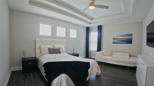 bedroom featuring dark hardwood / wood-style floors, ceiling fan, and a tray ceiling