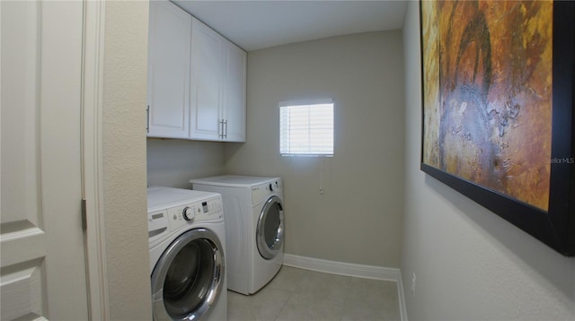 clothes washing area with light tile patterned floors, washing machine and dryer, and cabinets