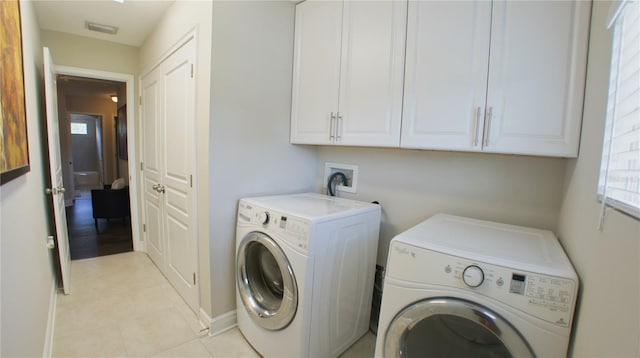 washroom featuring cabinets, washing machine and clothes dryer, and light tile patterned flooring