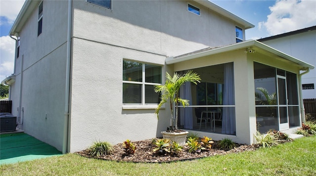 view of home's exterior with a sunroom, cooling unit, and a lawn