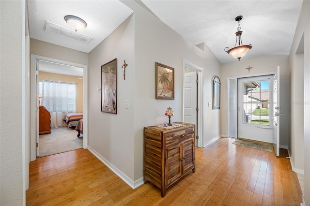 interior space with vaulted ceiling, light hardwood / wood-style floors, and a textured ceiling