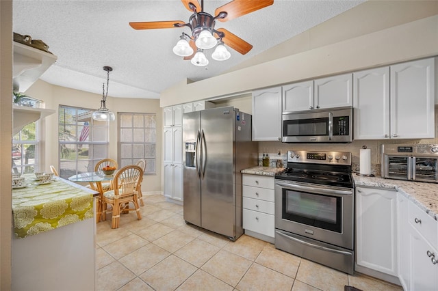 kitchen featuring lofted ceiling, white cabinetry, light tile patterned floors, pendant lighting, and stainless steel appliances