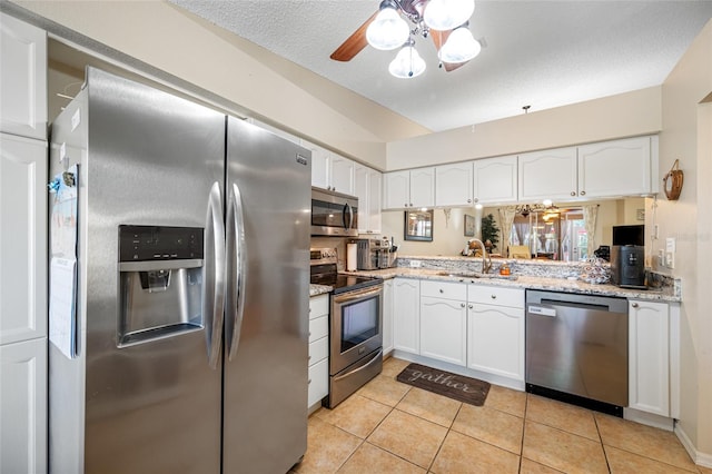 kitchen with stainless steel appliances, sink, light tile patterned floors, and white cabinets